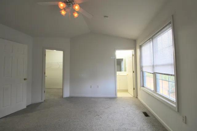 a view of an empty room with a window and a kitchen