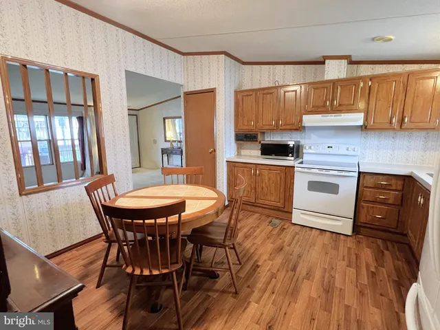a kitchen with stainless steel appliances granite countertop a kitchen island hardwood floor sink stove dining table and chairs