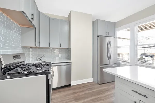 a kitchen with a refrigerator a stove a sink and white cabinets with wooden floor