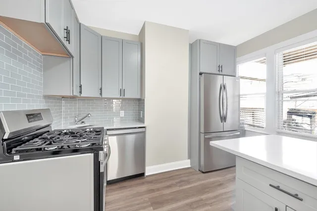 a kitchen with a refrigerator a stove a sink and white cabinets with wooden floor