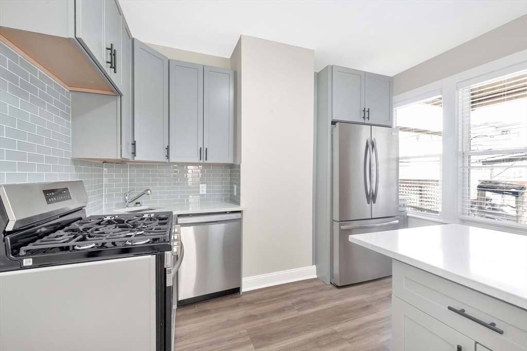 16 O Street, Unit 2 Boston, MA 02127 - Photo 10 of 19 a kitchen with a refrigerator a stove a sink and white cabinets with wooden floor