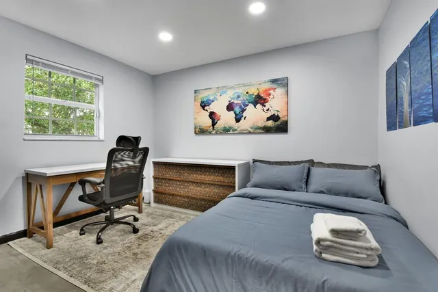 a bedroom with a bed and a dresser next to a window