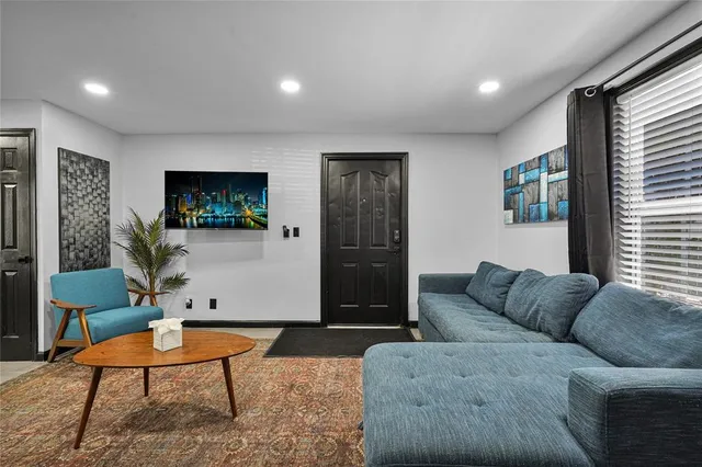 a living room with furniture kitchen view and a wooden floor