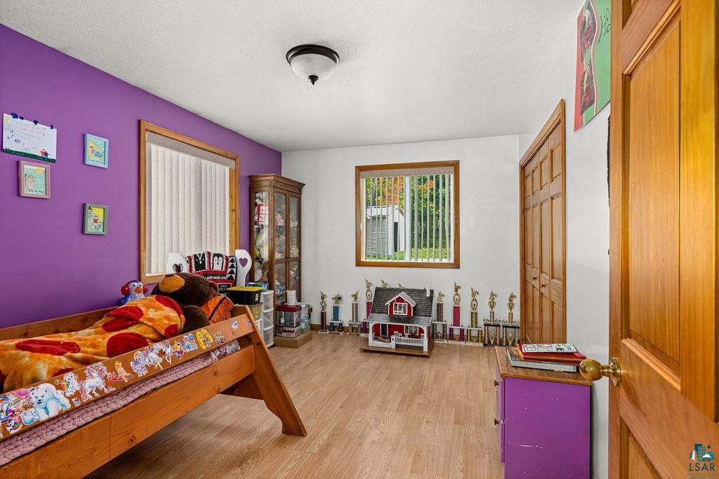 5466 Jean Duluth Road Duluth, MN 55803 - Photo 11 of 34 Wood-finish flooring, two windows with vertical blinds, a ceiling-mounted light fixture, and a paneled wooden door