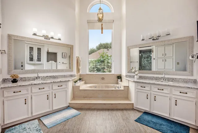 a spacious bathroom with a granite countertop tub a double vanity sink and a mirror