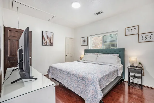 a bedroom with bed and a flat tv screen on dresser