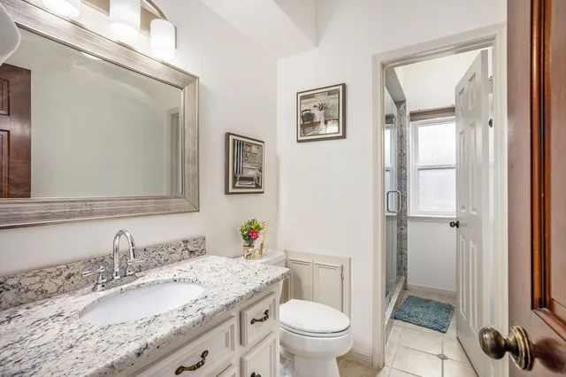 a bathroom with a granite countertop sink toilet and a mirror