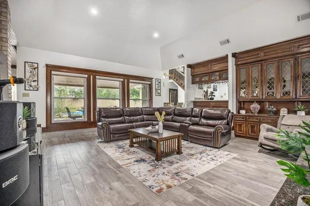 a living room with furniture large window and wooden floor