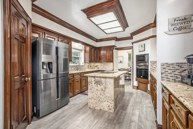a kitchen with stainless steel appliances granite countertop a refrigerator a stove and a wooden floors