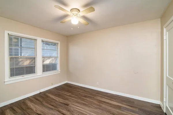 a view of an empty room with a window and wooden floor