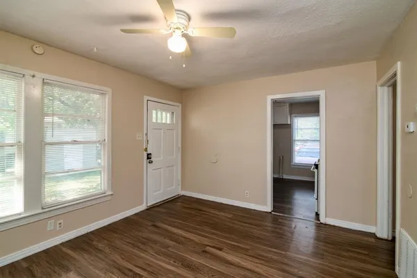 a view of an empty room with wooden floor and a window