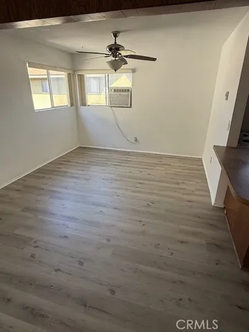 en empty room with wooden floor and fan