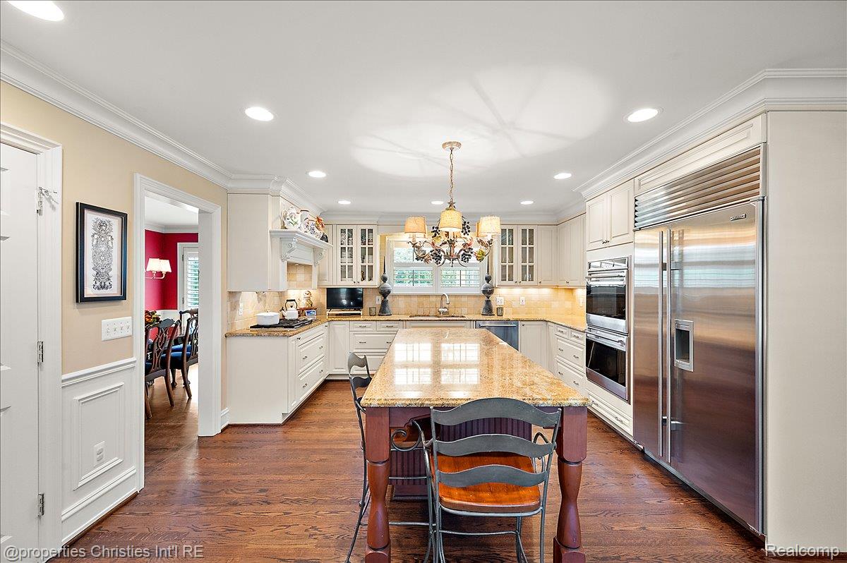 135 Clifton Road Bloomfield Hills, MI 48301 - Photo 24 of 77 Gourmet kitchen featuring a large central island with a granite countertop, wood-finish flooring, stainless steel appliances, recessed lighting, and white cabinetry