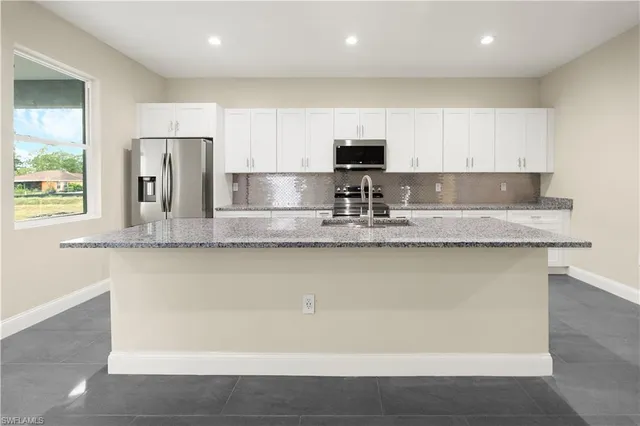 a kitchen with stainless steel appliances granite countertop a sink a refrigerator and a granite counter tops