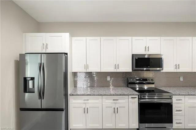 a kitchen with stainless steel appliances granite countertop a refrigerator a stove and white cabinets