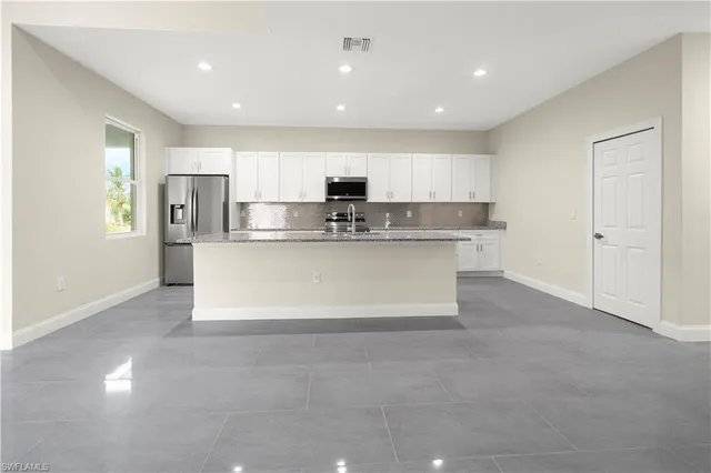 a view of kitchen with stainless steel appliances granite countertop a stove top oven a sink and a refrigerator