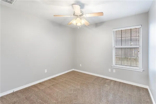 an empty room with windows and fan
