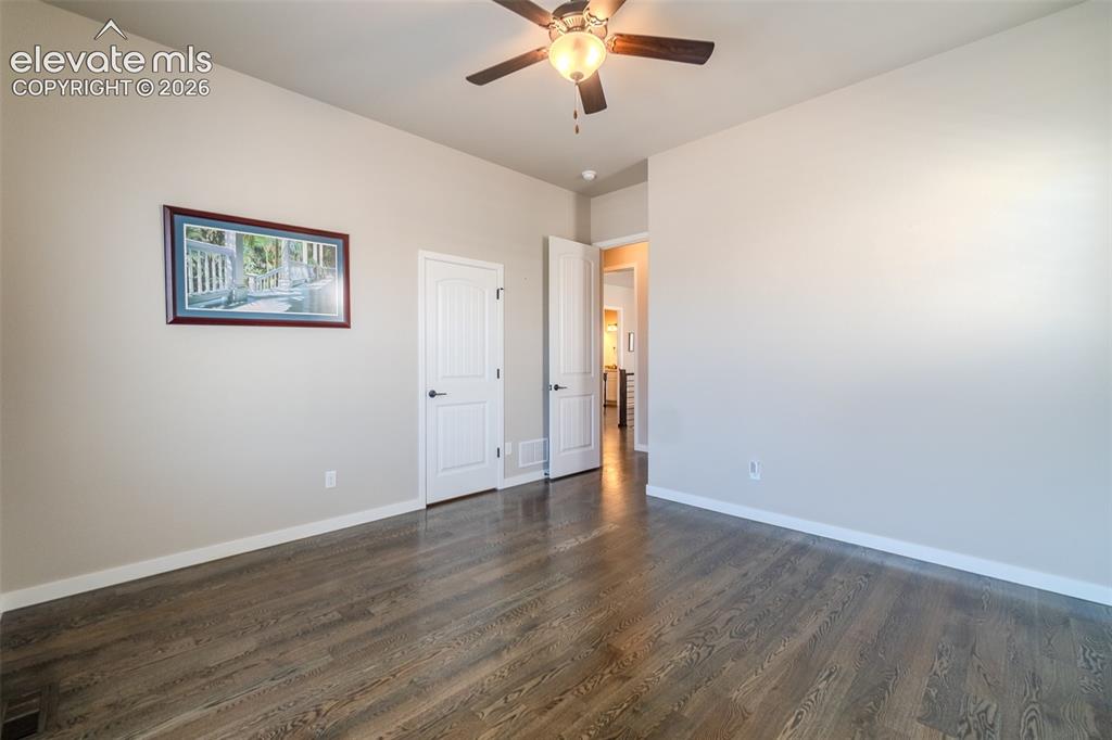 1061 Native Dancer Terrace Colorado Springs, CO 80921 - Photo 18 of 50 Spacious room featuring wood-finish flooring, two windows with white louvered shutters, a ceiling fan with integrated lighting, and neutral wall paint