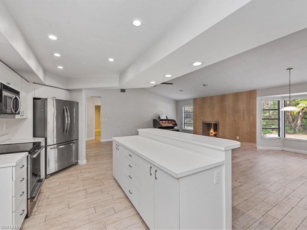 7016 Trail Boulevard Naples, FL 34108 - Photo 12 of 26 a large white kitchen with wooden floor and stainless steel appliances