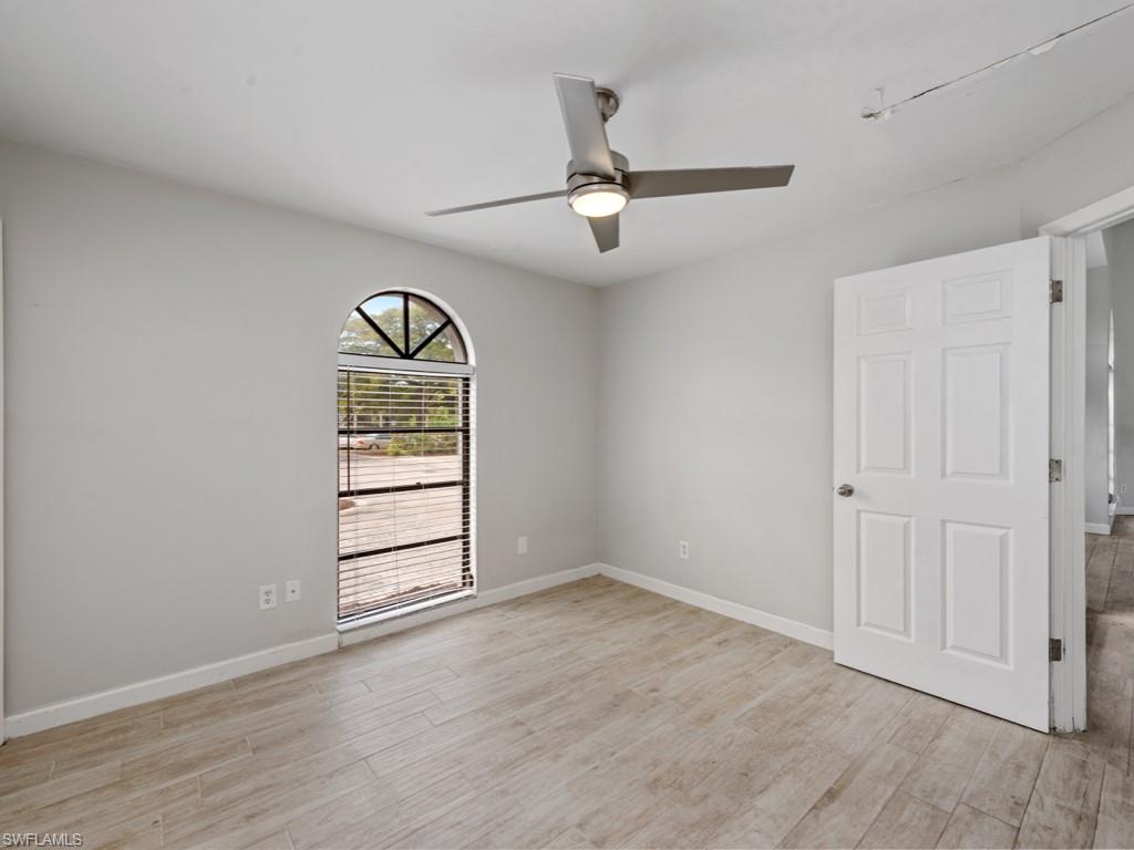 7016 Trail Boulevard Naples, FL 34108 - Photo 19 of 26 an empty room with wooden floor closet ceiling fan and windows