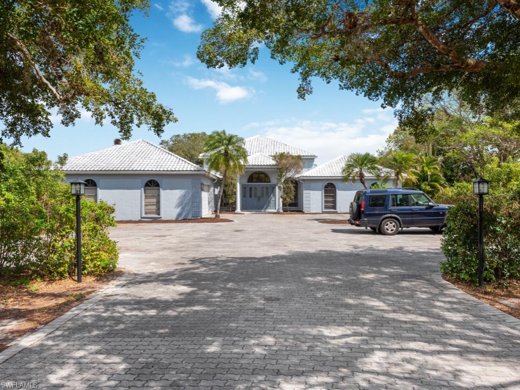 7016 Trail Boulevard Naples, FL 34108 - Photo 2 of 26 a front view of a house with a garden