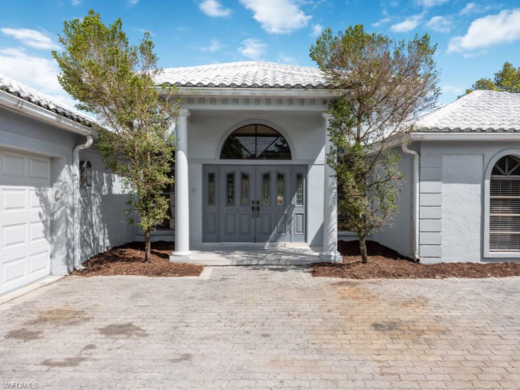 7016 Trail Boulevard Naples, FL 34108 - Photo 3 of 26 a front view of a house with a yard