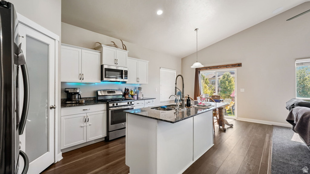 6062 Spring Street Stansbury Park, UT 84074 - Photo 6 of 36 Open-concept kitchen featuring white cabinetry, stainless steel appliances, granite countertops, a center island with a sink, and LVP