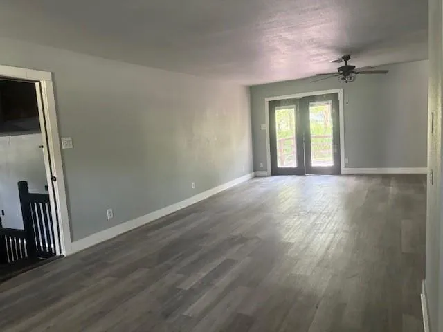 a view of an empty room with wooden floor and a window