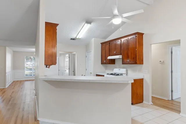 a kitchen with stainless steel appliances granite countertop a refrigerator a sink a stove with wooden cabinets