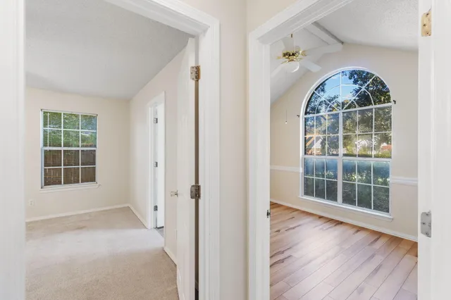 an empty room with wooden floor fan and windows