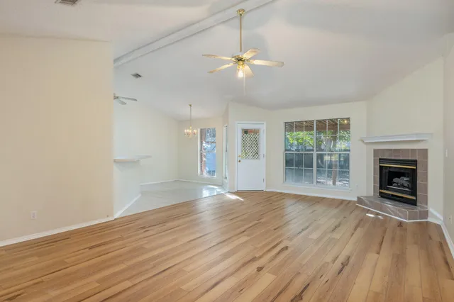 a view of an empty room with wooden floor fireplace and a window