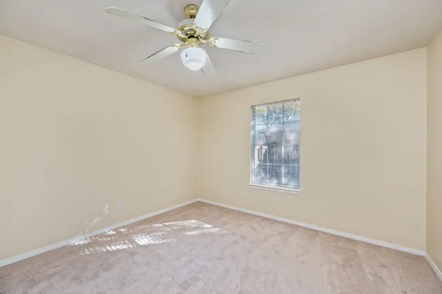 an empty room with a chandelier fan and windows