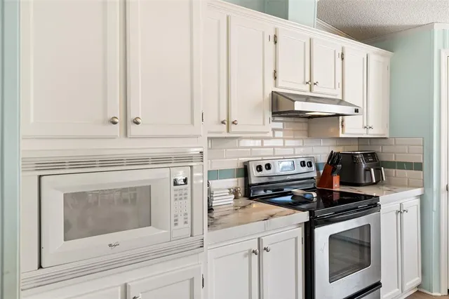 a kitchen with white cabinets and appliances