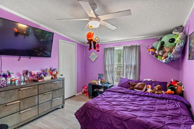 a bedroom with a bed potted plant on the dresser and a window
