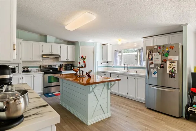 a kitchen with stainless steel appliances granite countertop a refrigerator a stove a sink dishwasher and a refrigerator with wooden floor