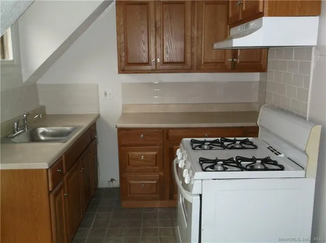 a kitchen with granite countertop a sink stove and cabinets