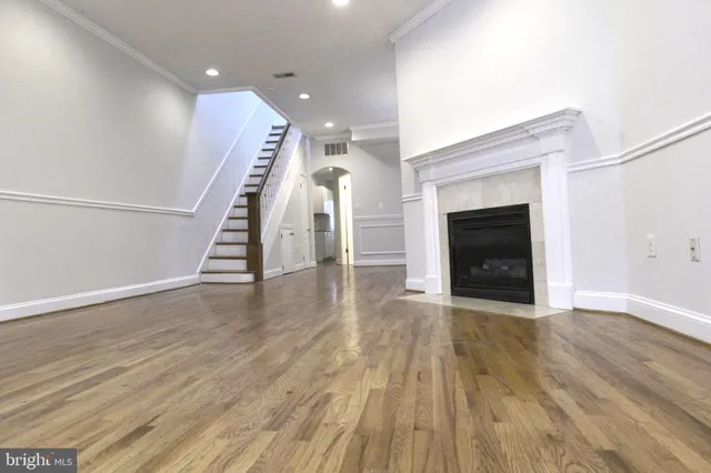 an entryway and an empty room with wooden floor