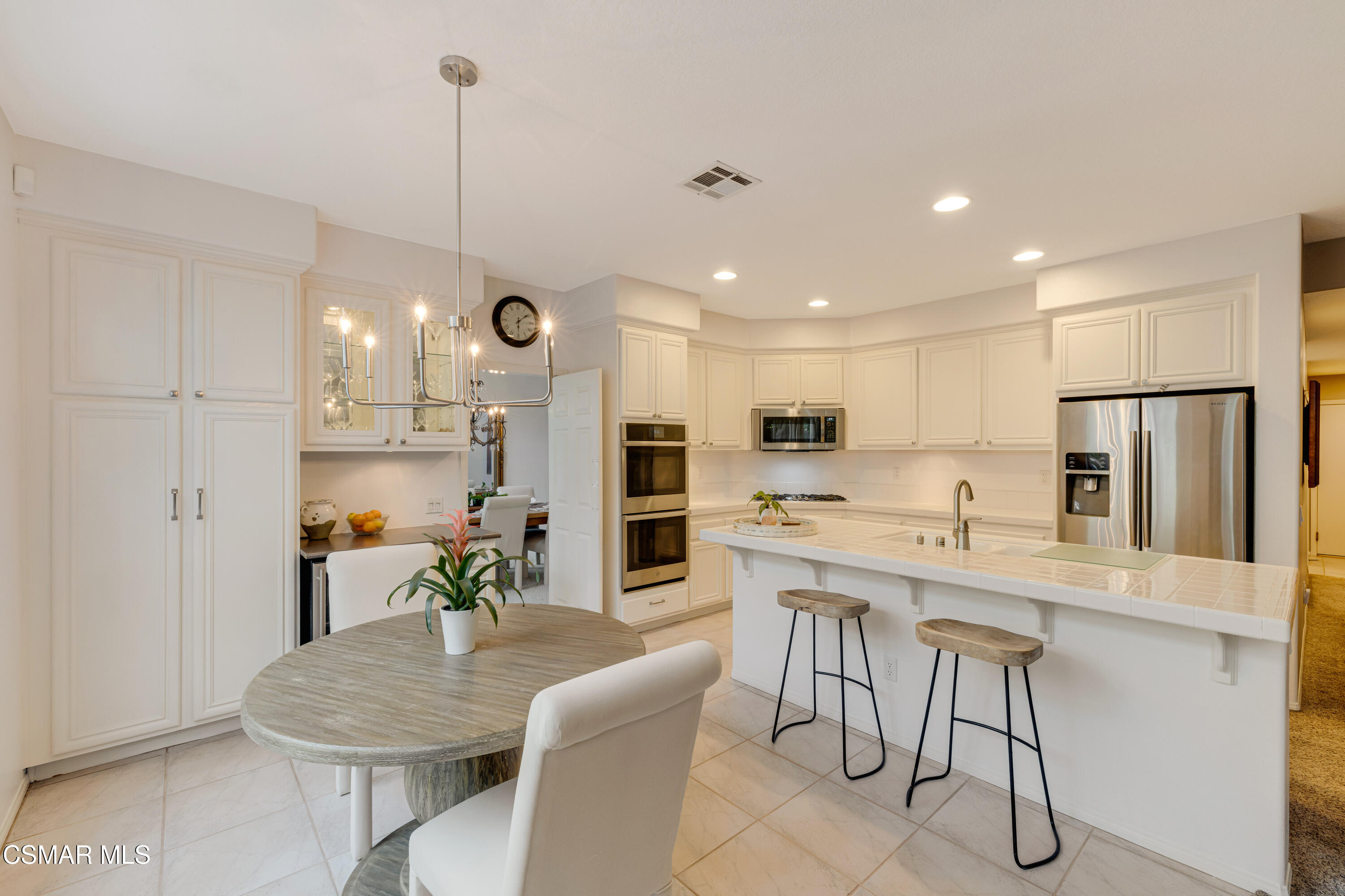 15633 Harte Lane Moorpark, CA 93021 - Photo 24 of 64 a kitchen with stainless steel appliances kitchen island granite countertop a dining table chairs refrigerator and microwave