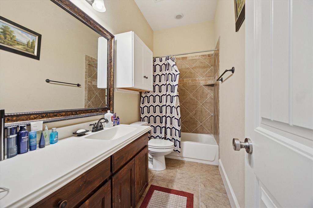 119 George Owens Road Ponder, TX 76259 - Photo 17 of 26 Bathroom featuring a wood-finish vanity with an integrated sink, a large framed mirror, and a shower-over-tub combination with tile surround