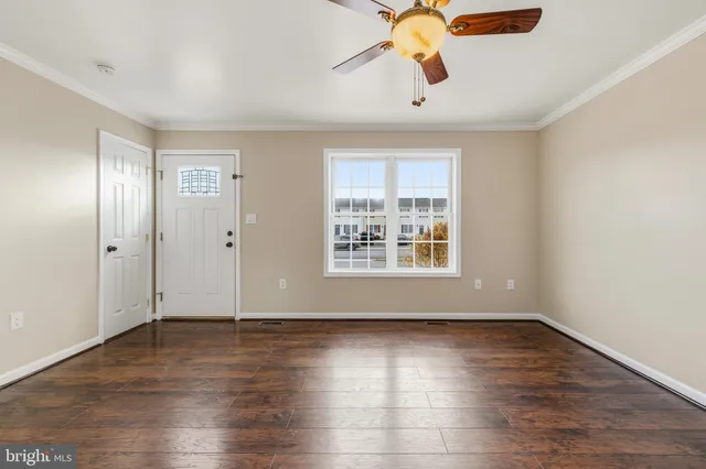 an empty room with wooden floor chandelier fan and windows