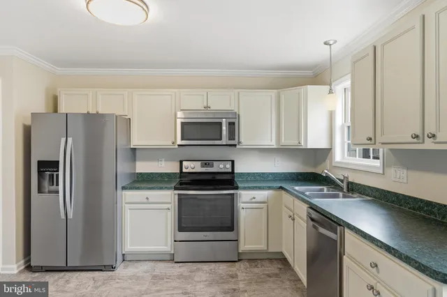 a kitchen with a sink white cabinets and stainless steel appliances