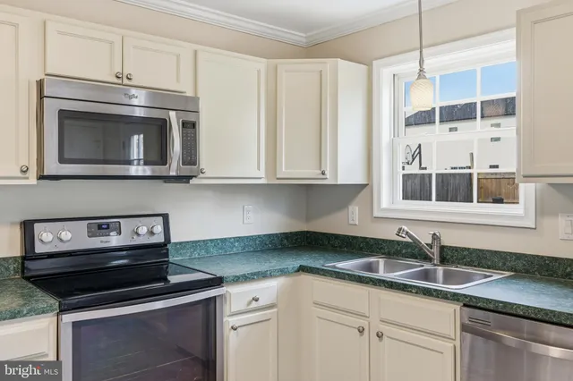 a kitchen with stainless steel appliances granite countertop white cabinets and a stove top oven