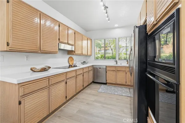 a kitchen with a sink cabinets stainless steel appliances and a window