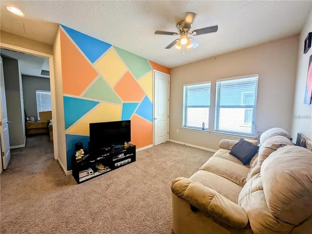 a living room with furniture a flat screen tv and a window
