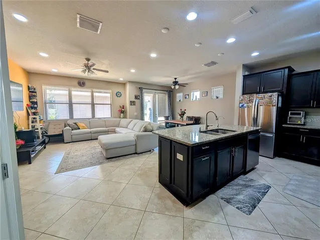 a kitchen with kitchen island granite countertop a counter top space appliances and a view of living room