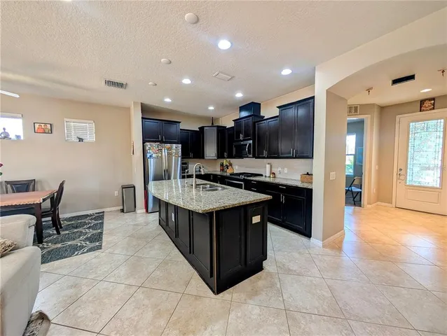 a kitchen with kitchen island granite countertop a sink and a refrigerator