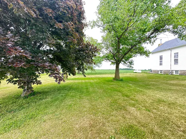 a view of grassy field with benches and trees all around