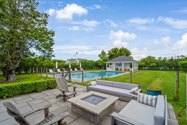 a view of a patio with couches chairs and a table and chairs with wooden floor and fence