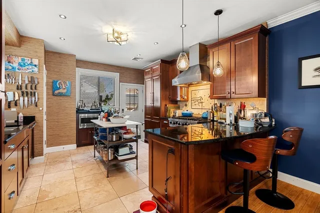 a kitchen with granite countertop a stove a sink a dining table and chairs