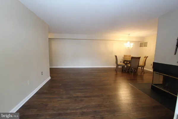 an empty room with wooden floor and dining room view